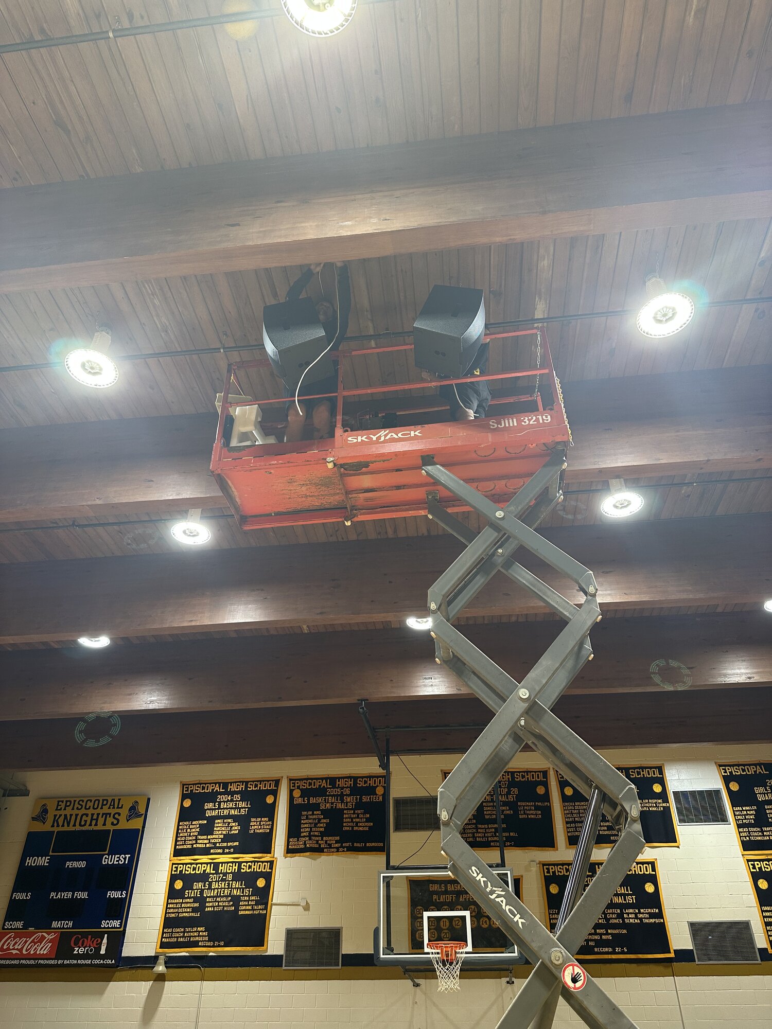 Tight detail of two Blaze loudspeakers hung between dark wood ceiling beams, with cabling routed cleanly along the beam line.