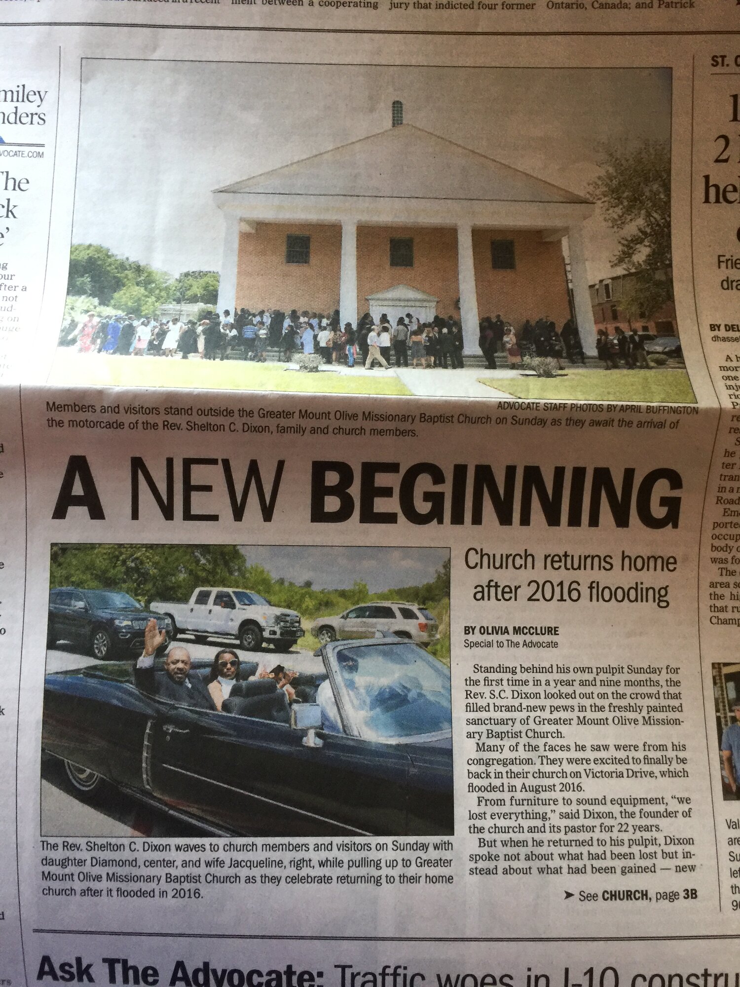 Newspaper article from The Advocate titled "A NEW BEGINNING: Church returns home after 2016 flooding" with photos of Reverend Shelton C. Dixon waving from a car and the congregation gathered outside the brick sanctuary.