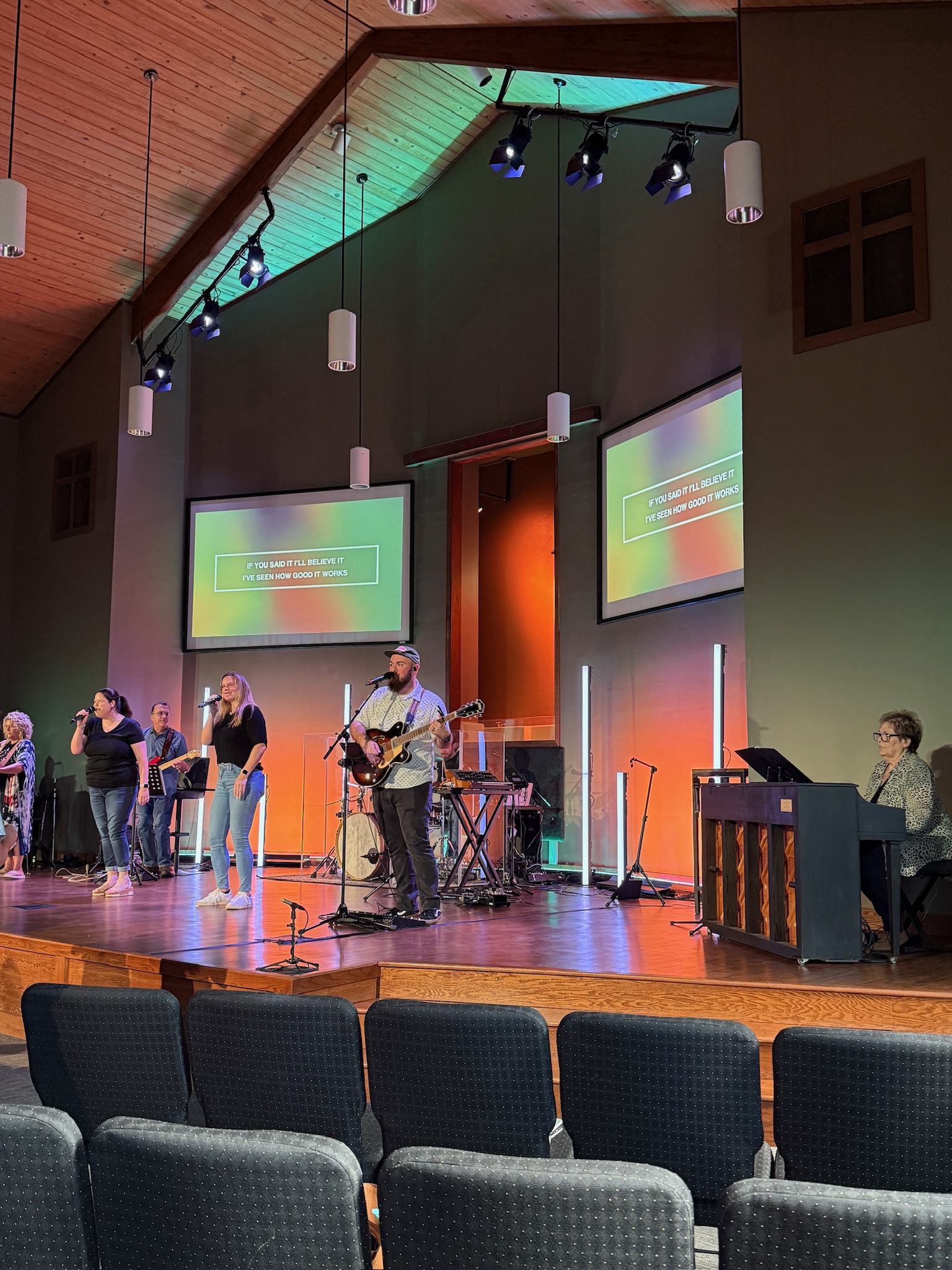 Istrouma Ascension sanctuary in a programmed lighting state — back-wall wash and overhead bar combining with the band on the platform.