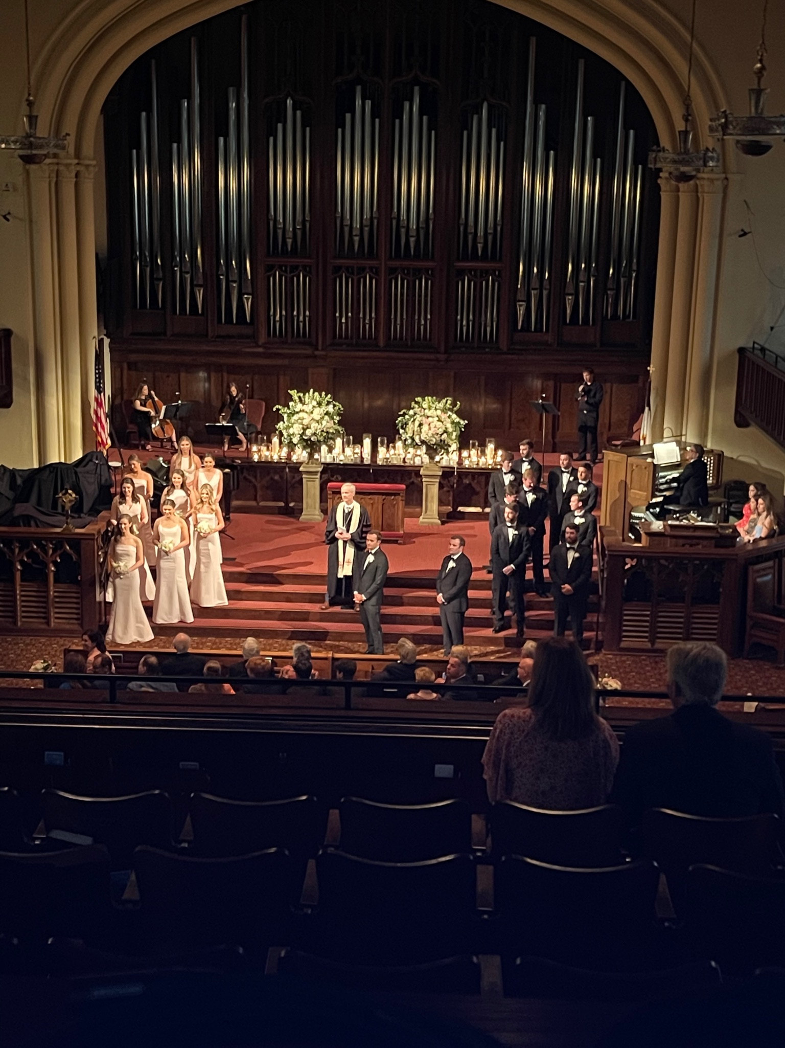 FPCBR Christmas service with deep blue architectural uplighting on the gothic stone arch and organ pipes, performance arrangement on the platform, poinsettias lining the steps.