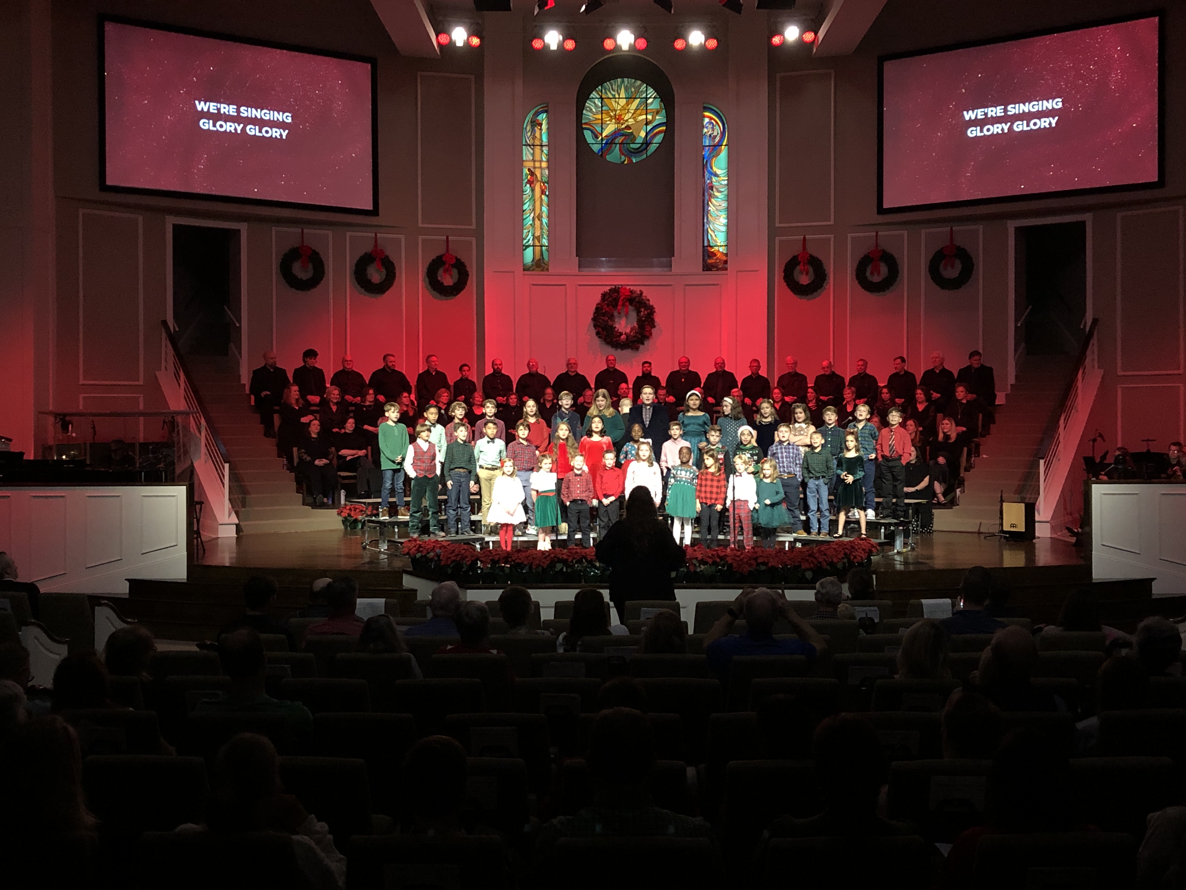 Jefferson Baptist Christmas program in service — choir, band, and congregation all active under the dual side screens.