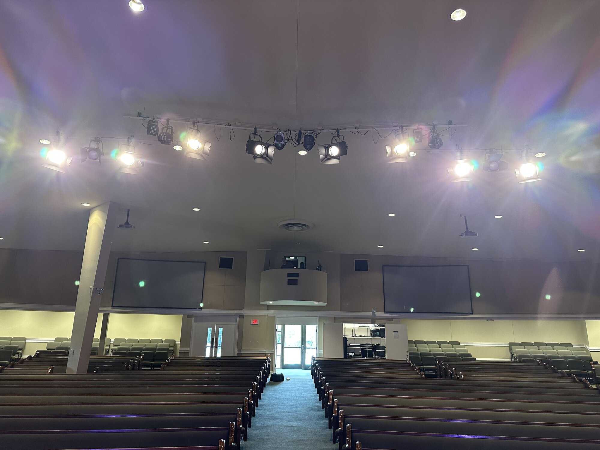 Tight detail of theatrical fresnels and a blue PAR fixture mounted to a ceiling pipe at Parkview Baptist, showing the layered fixture array hung overhead.