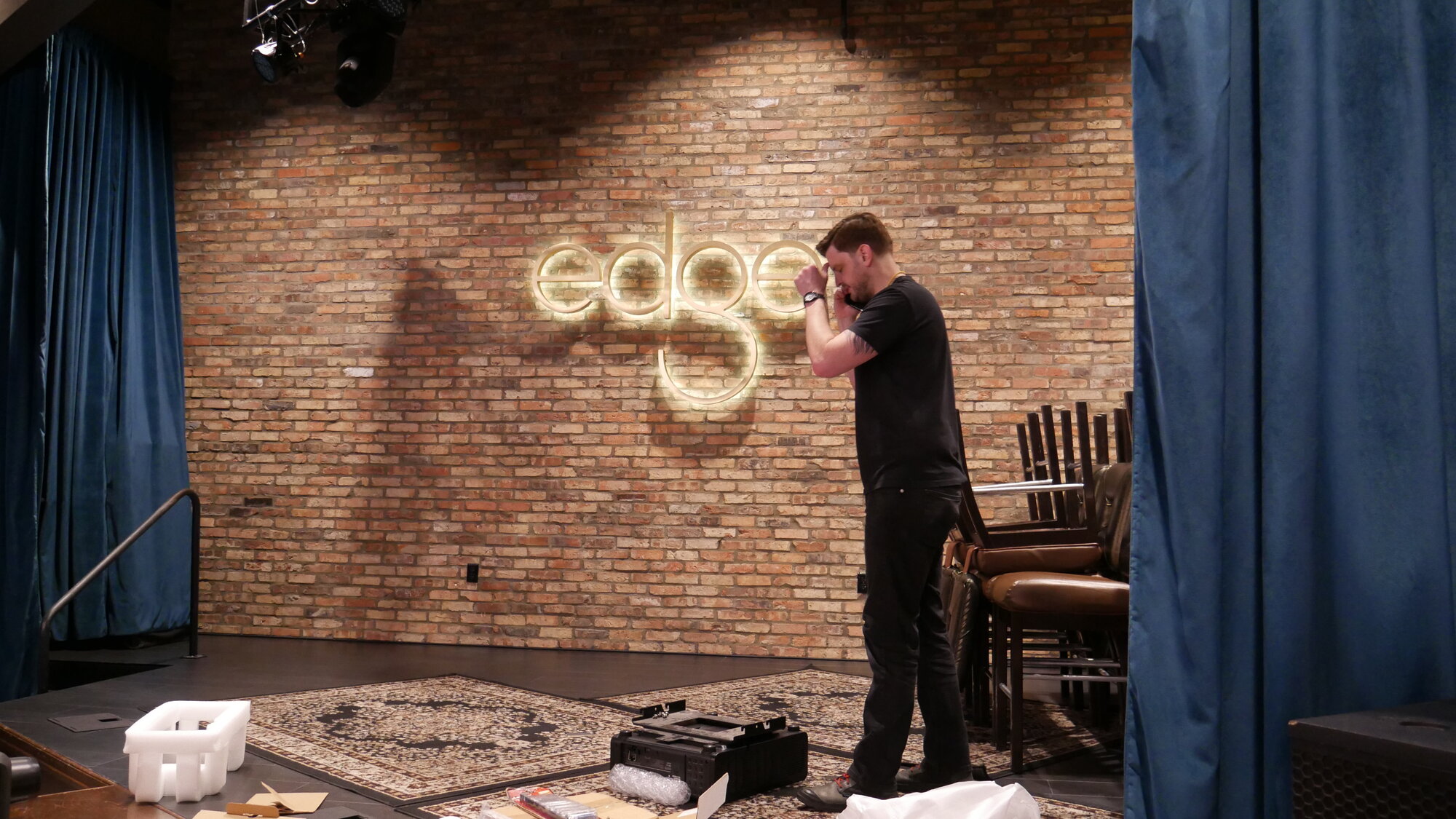 Hands-on detail at the projector — technician aligning lens or adjusting the dowser hardware during commissioning.